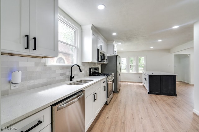 kitchen featuring white cabinets, appliances with stainless steel finishes, light hardwood / wood-style flooring, and sink