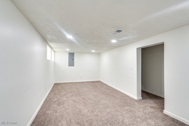 basement featuring carpet flooring, electric panel, and a textured ceiling