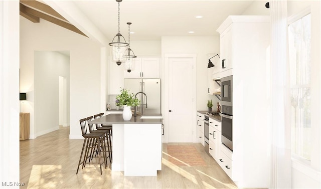 kitchen featuring pendant lighting, a breakfast bar, white cabinets, and stainless steel appliances