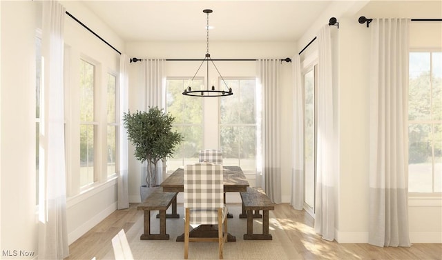 dining room with a wealth of natural light, light hardwood / wood-style floors, and an inviting chandelier