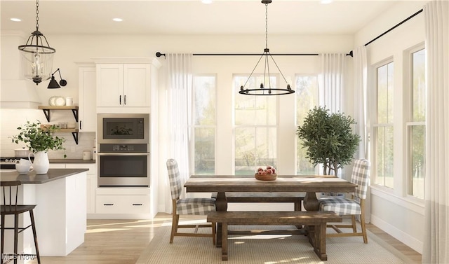 kitchen featuring white cabinetry, hanging light fixtures, light hardwood / wood-style flooring, backsplash, and oven