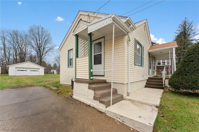 view of front of house featuring a porch, a front lawn, an outdoor structure, and a garage