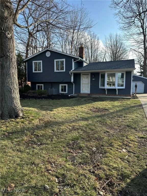 tri-level home with a front yard, an outbuilding, central AC, and a garage