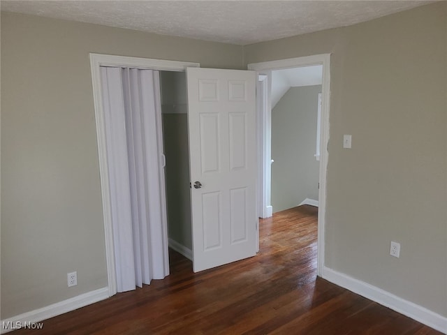 interior space featuring a textured ceiling, dark hardwood / wood-style flooring, a closet, and lofted ceiling