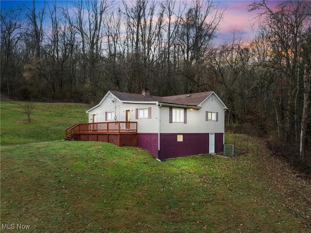 property exterior at dusk featuring a deck and a yard