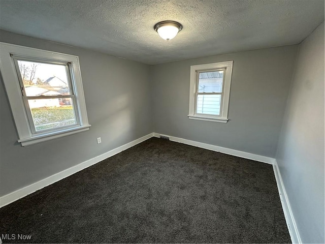 spare room with dark carpet and a textured ceiling