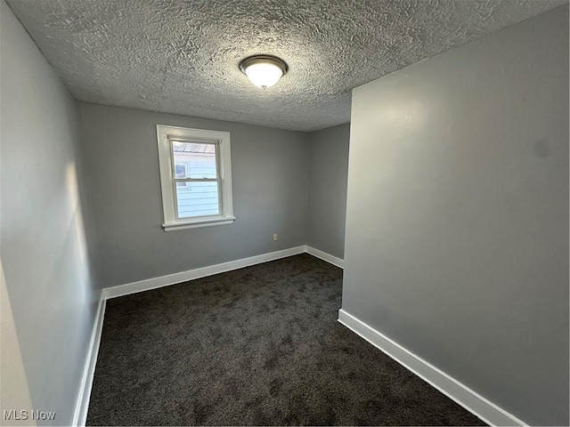 empty room featuring dark carpet and a textured ceiling