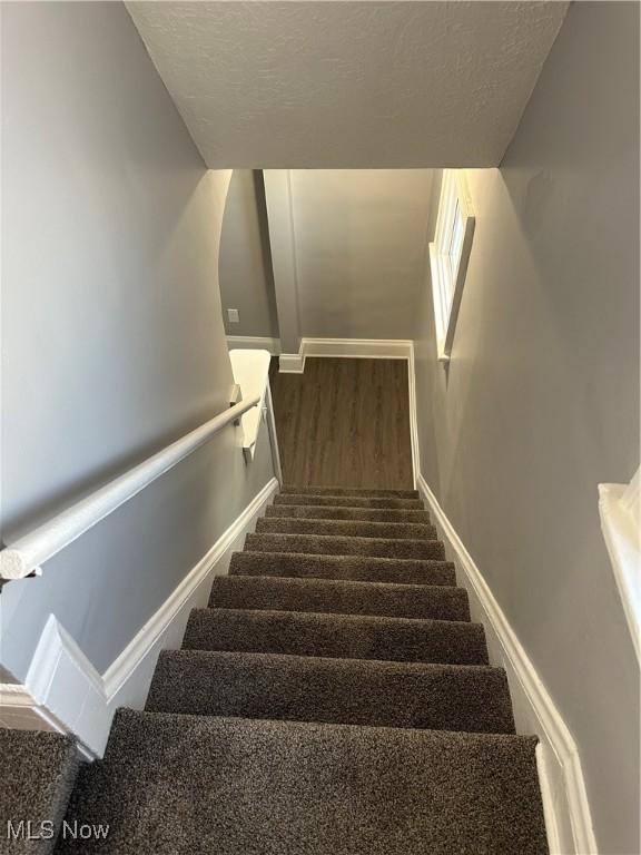 stairs featuring a textured ceiling and hardwood / wood-style flooring