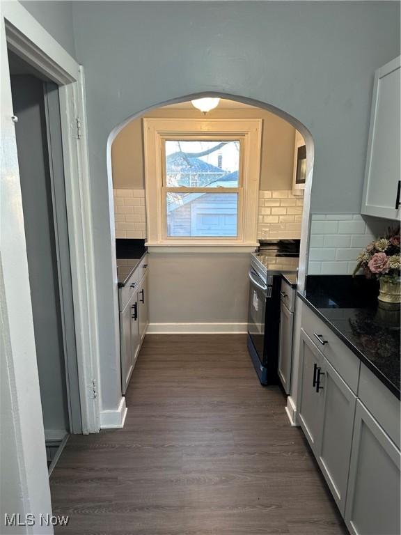 kitchen with tasteful backsplash, white cabinetry, dark hardwood / wood-style flooring, and stainless steel range with electric cooktop