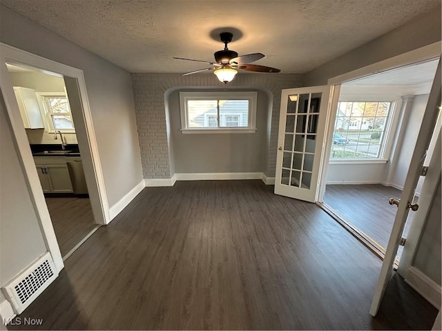 unfurnished dining area featuring a textured ceiling, dark wood-type flooring, and a healthy amount of sunlight