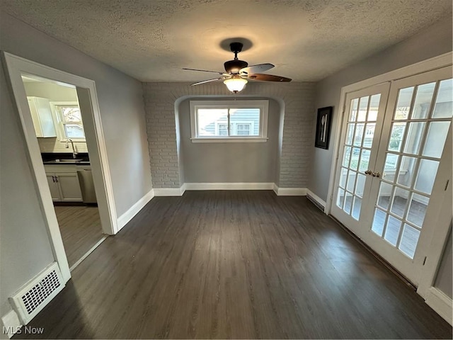 unfurnished room featuring ceiling fan, french doors, sink, dark hardwood / wood-style floors, and a textured ceiling