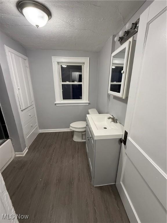 bathroom with hardwood / wood-style flooring, vanity, toilet, and a textured ceiling