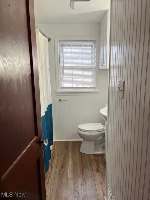 bathroom with toilet, wood-type flooring, and wooden walls