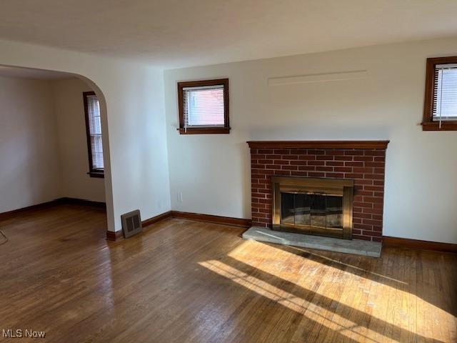 unfurnished living room featuring a wealth of natural light, a fireplace, and dark hardwood / wood-style floors