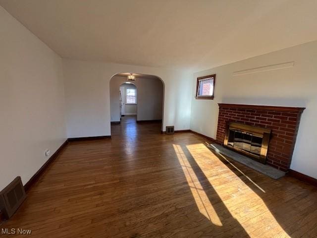 unfurnished living room with dark hardwood / wood-style floors and a brick fireplace