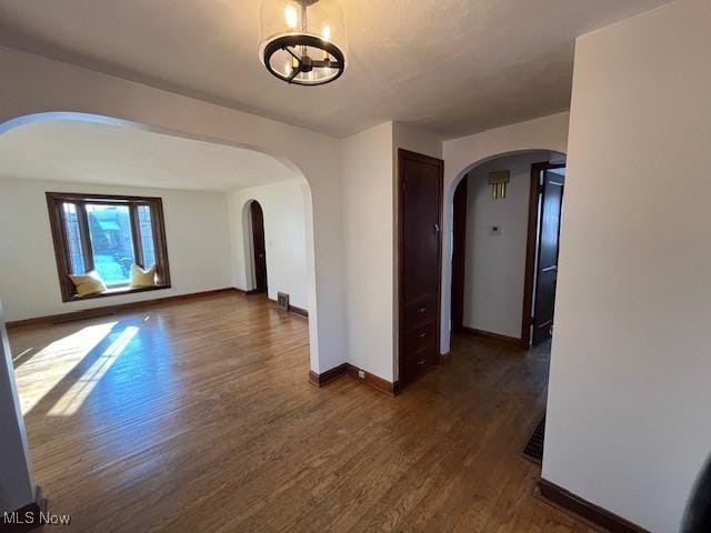 spare room with a chandelier and dark hardwood / wood-style flooring