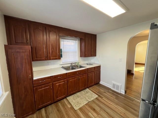 kitchen with stainless steel fridge, sink, and light hardwood / wood-style floors