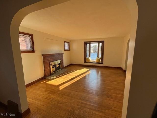 unfurnished living room with a brick fireplace and hardwood / wood-style flooring