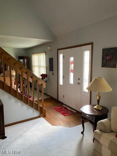 foyer with vaulted ceiling and baseboards