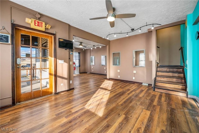 unfurnished living room featuring hardwood / wood-style flooring, ceiling fan, a textured ceiling, and a wealth of natural light