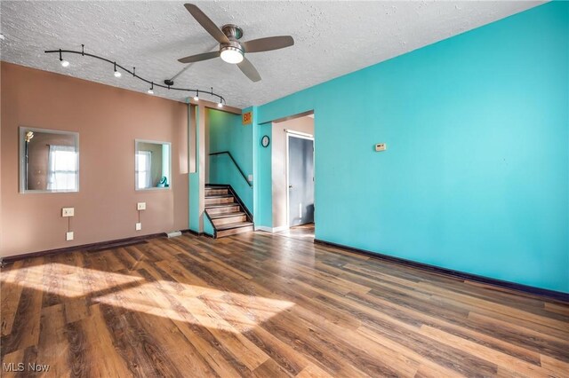 unfurnished living room with ceiling fan, track lighting, wood-type flooring, and a textured ceiling