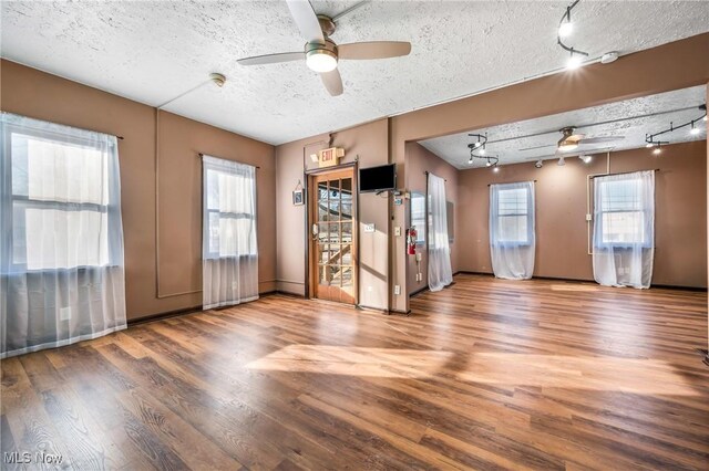 spare room featuring hardwood / wood-style floors, ceiling fan, a textured ceiling, and rail lighting