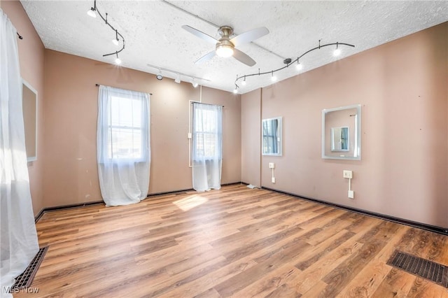 spare room with ceiling fan, light wood-type flooring, a textured ceiling, and track lighting