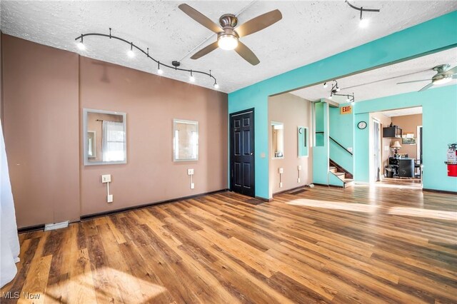 interior space with hardwood / wood-style floors, a textured ceiling, and rail lighting