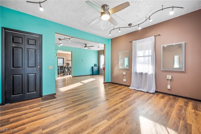 entryway with ceiling fan, hardwood / wood-style floors, track lighting, and a textured ceiling