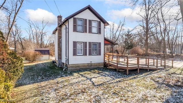 rear view of house with a storage shed and a wooden deck