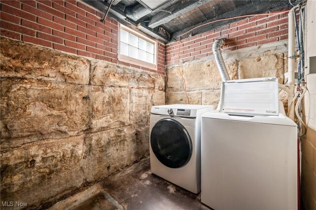 laundry room with washer and dryer and brick wall