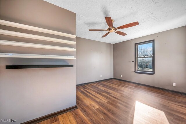 unfurnished room with a textured ceiling, ceiling fan, and dark hardwood / wood-style floors