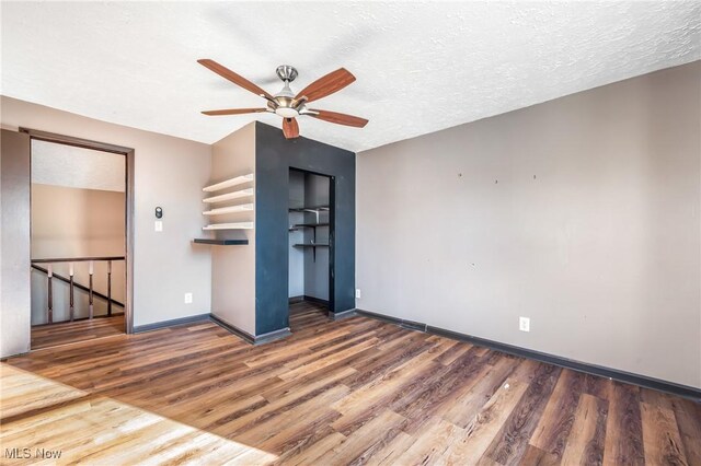 empty room featuring ceiling fan, dark hardwood / wood-style flooring, and a textured ceiling