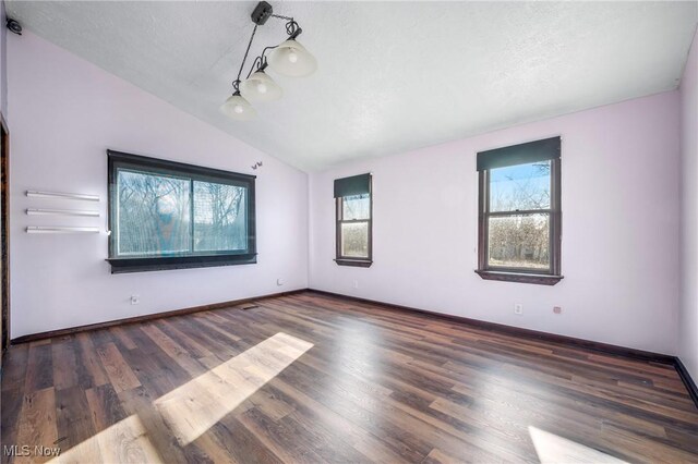 unfurnished room with a textured ceiling, dark wood-type flooring, and vaulted ceiling