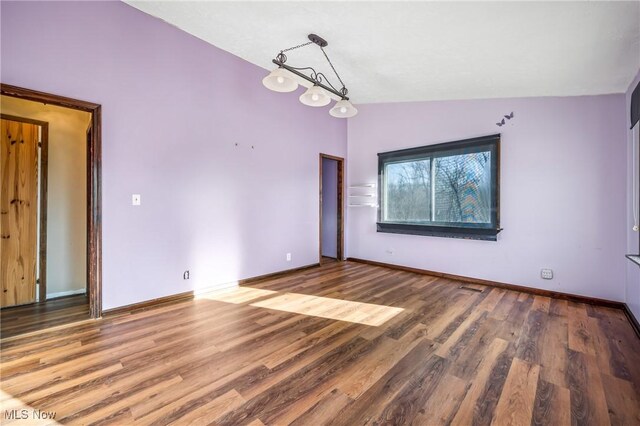 empty room with hardwood / wood-style flooring and vaulted ceiling