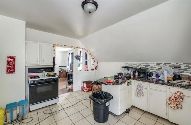 kitchen featuring kitchen peninsula, vaulted ceiling, white range with gas cooktop, decorative backsplash, and white cabinets