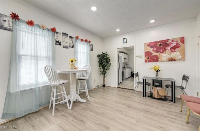 dining room featuring crown molding and light hardwood / wood-style flooring