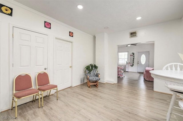 interior space with ceiling fan, light wood-type flooring, and ornamental molding