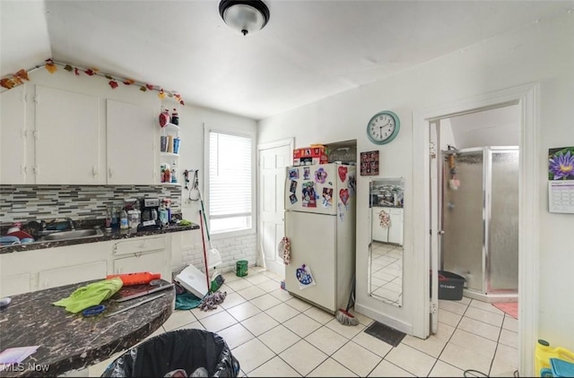 kitchen featuring sink, white cabinets, light tile patterned flooring, and white refrigerator