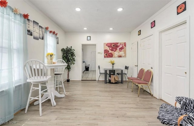 living area with light hardwood / wood-style floors, crown molding, and a wealth of natural light