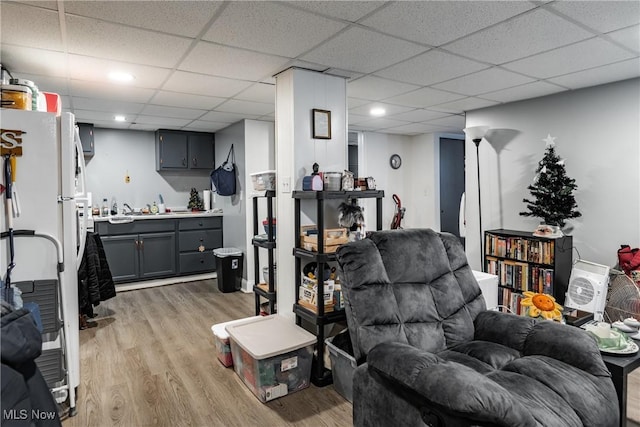 living room with light hardwood / wood-style flooring and a drop ceiling