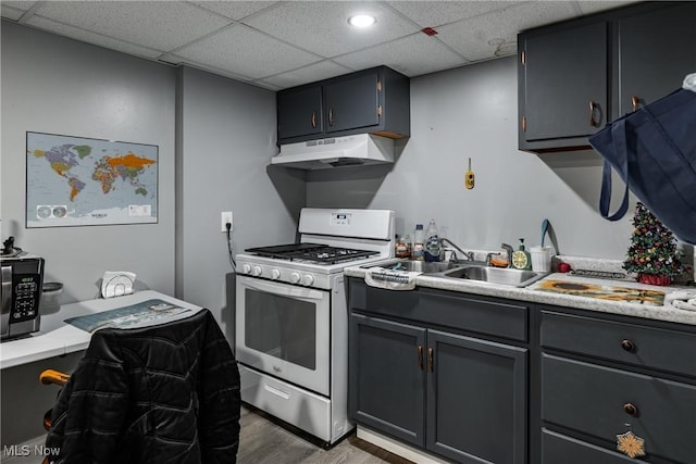 kitchen featuring a drop ceiling, gas range oven, sink, wood-type flooring, and gray cabinets