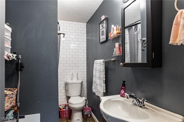 bathroom featuring sink, a shower with curtain, a textured ceiling, toilet, and tile walls