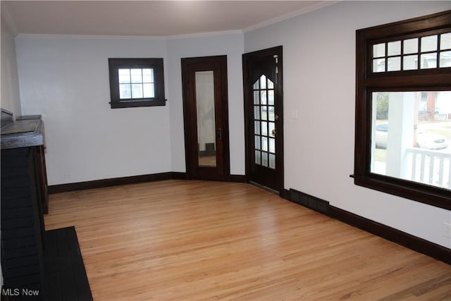 interior space with a wealth of natural light, light hardwood / wood-style flooring, and ornamental molding