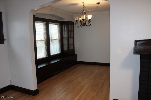 unfurnished dining area with a chandelier, wood-type flooring, and ornamental molding