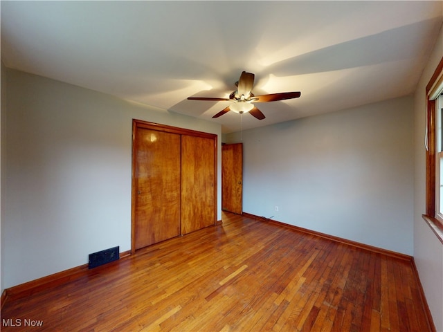 unfurnished bedroom with ceiling fan, a closet, and light wood-type flooring