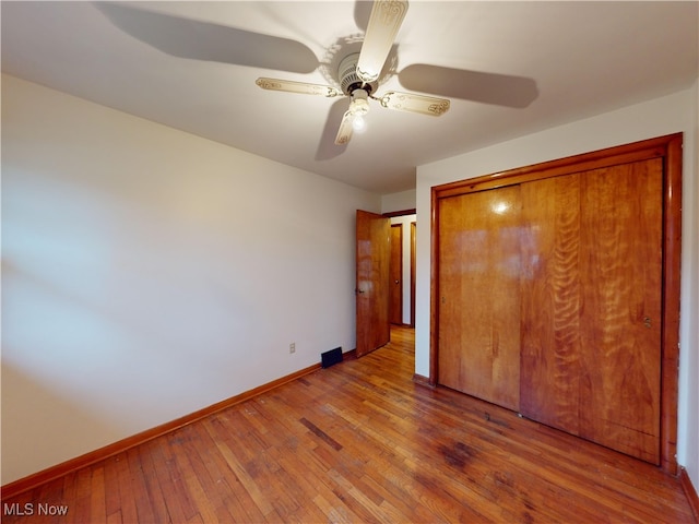 unfurnished bedroom featuring a closet, light hardwood / wood-style flooring, and ceiling fan