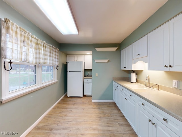 kitchen with white cabinetry, light hardwood / wood-style flooring, white fridge, and sink