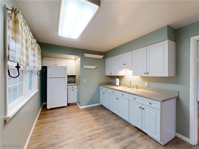 kitchen featuring white cabinets, light hardwood / wood-style flooring, white fridge, and sink