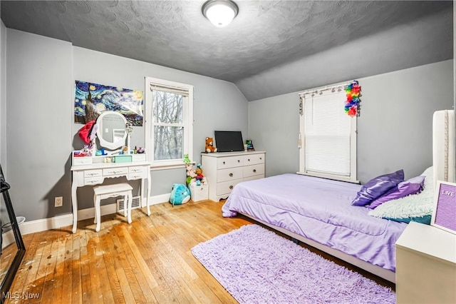 bedroom featuring a textured ceiling, lofted ceiling, and light wood-type flooring